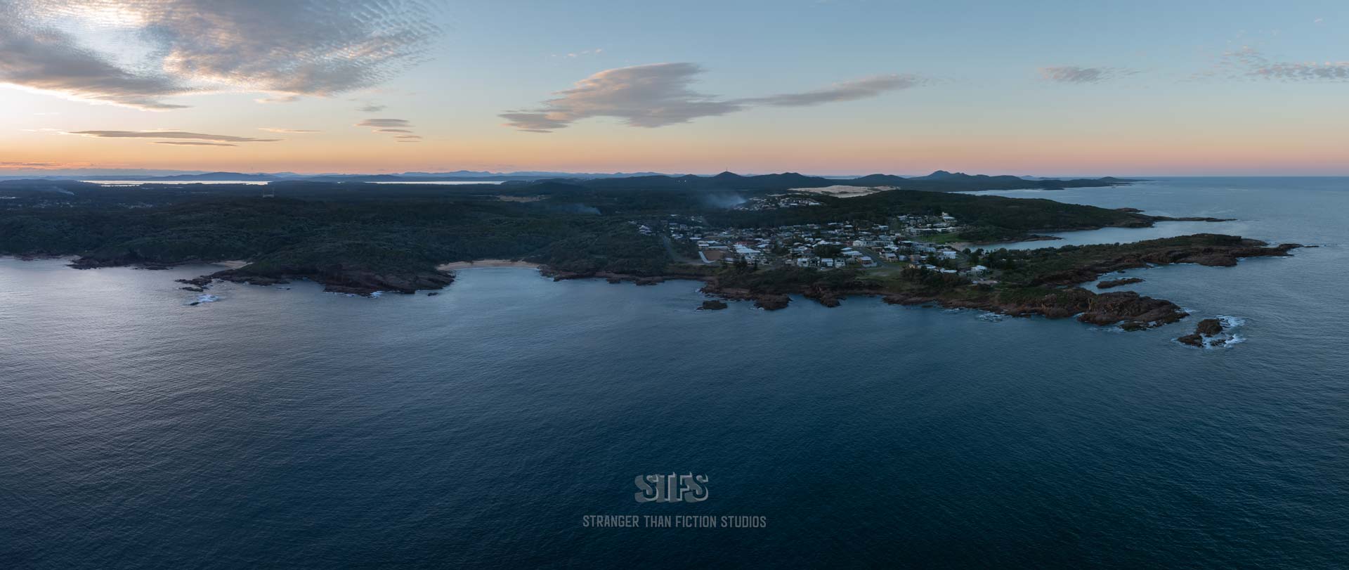 Panoramic Drone Image Of The Port Stephens Coastline From Boat Harbour To Anna Bay. Captured At Sunset With Golden Sky Above And Sand Dunes Behind.